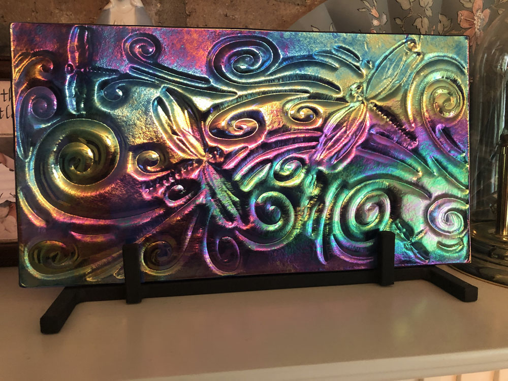 A striking fused glass panel with luminescent swirls and dragonflies in vibrant rainbow colors, creating a mesmerizing effect.